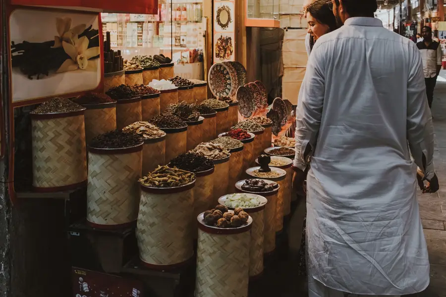 A trader beside open sacks of spices in a Dubai souk