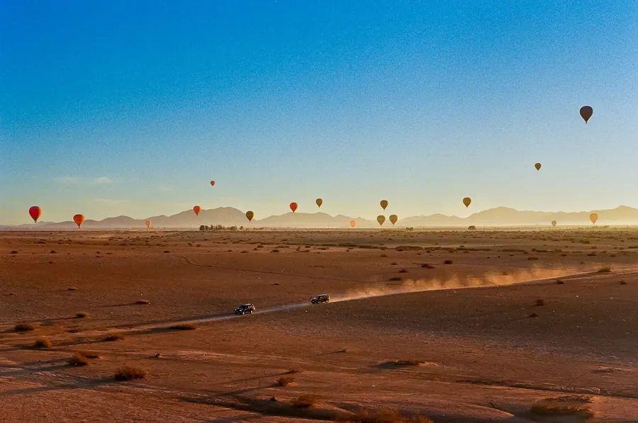 Hot air balloons rising over the desert at sunrise