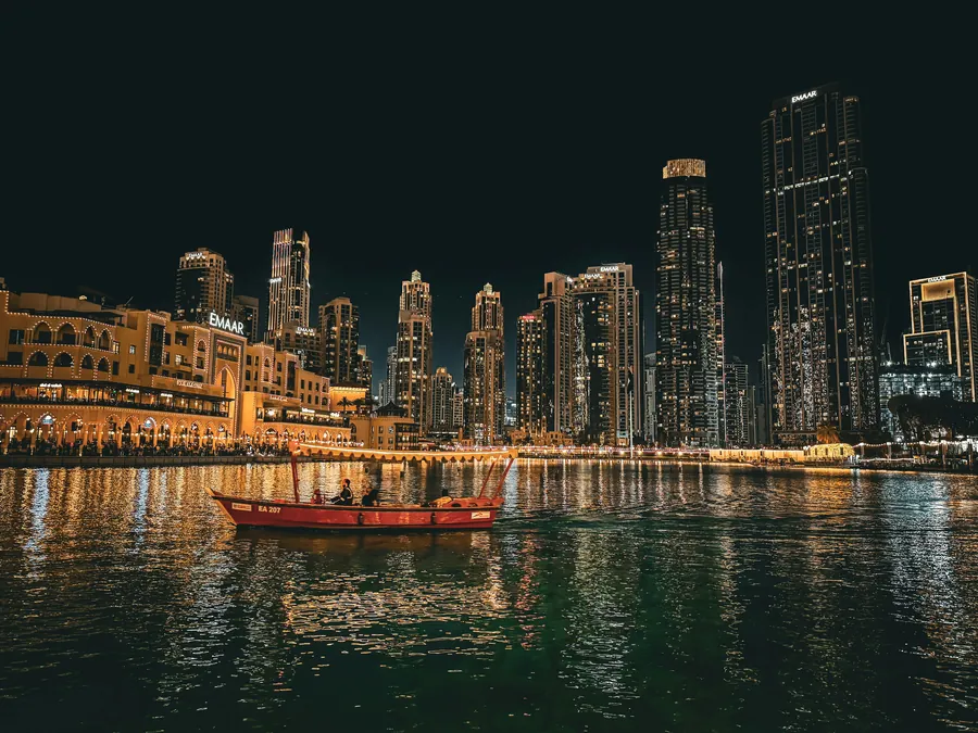 A traditional boat on the lake below the Downtown Dubai skyline at night