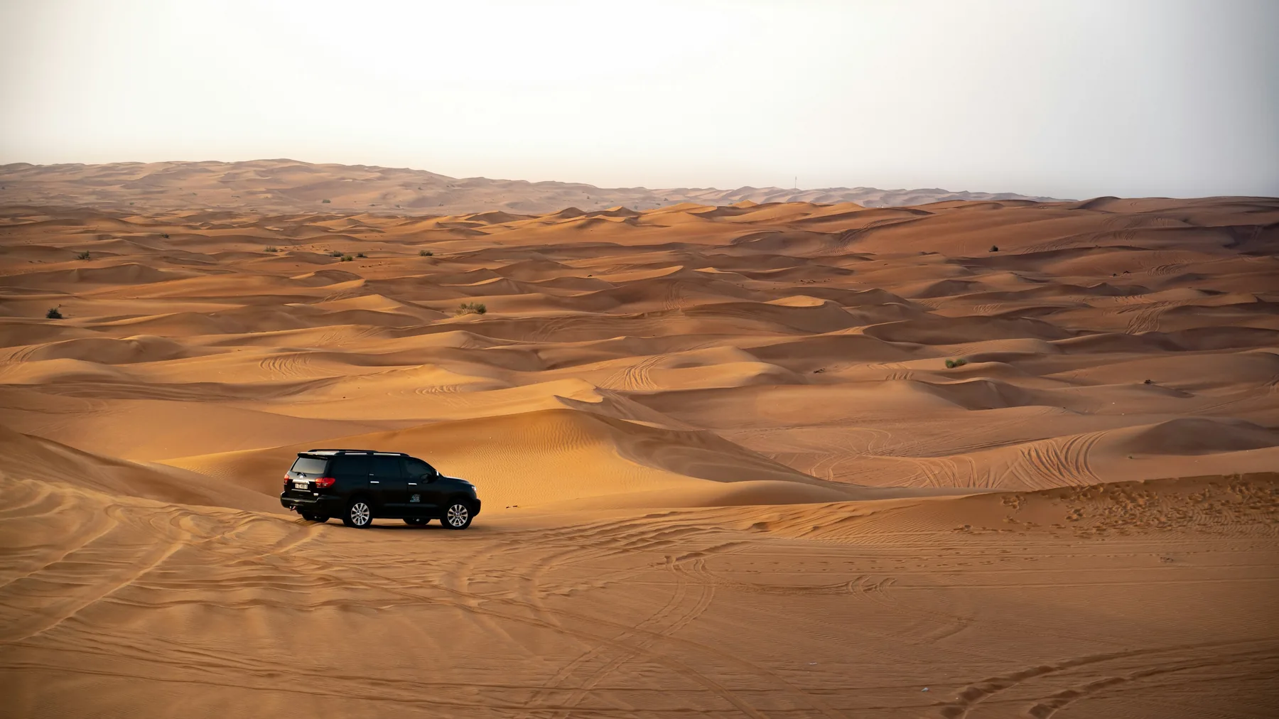 A 4x4 driving across wide red dunes