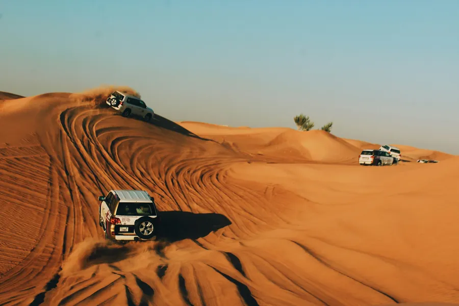 4x4 vehicles climbing red dunes on a desert safari