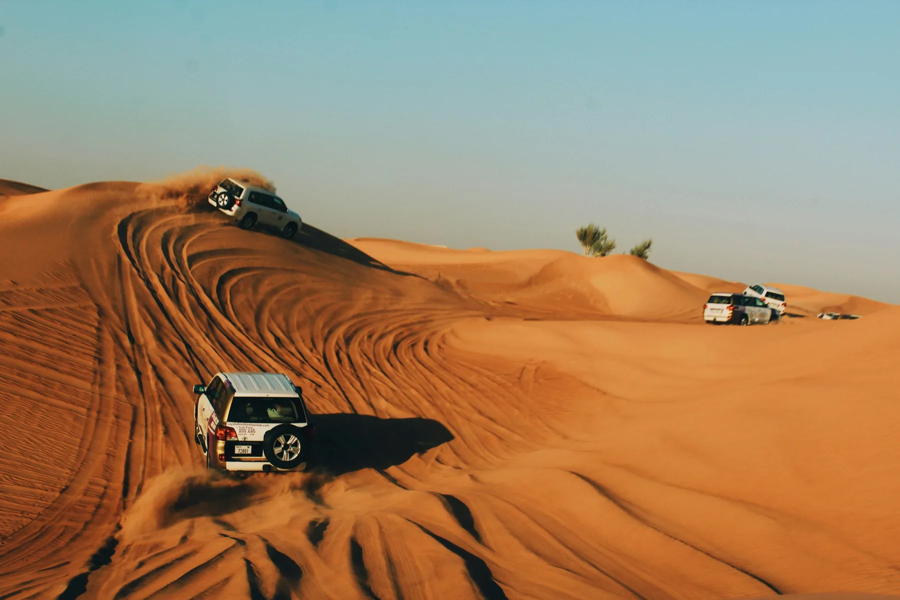 4x4 vehicles climbing red dunes on a desert safari