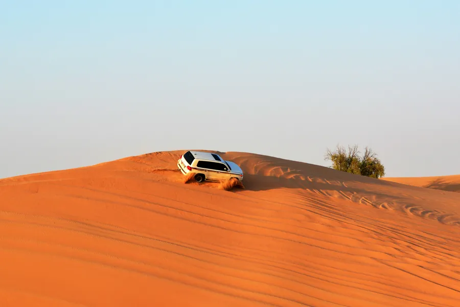 A 4x4 cresting a bright red dune