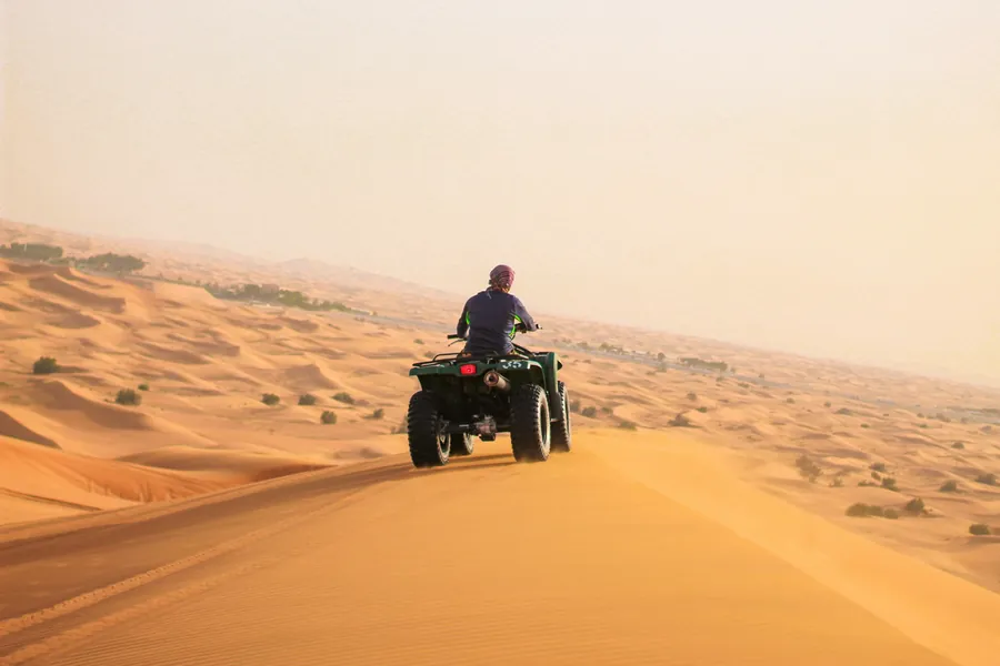 A rider on a quad bike on top of a sand dune
