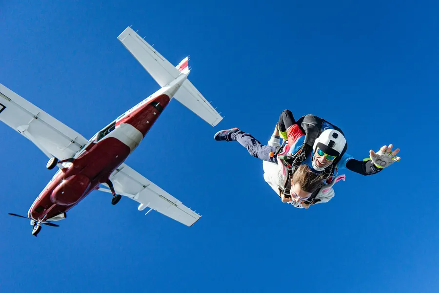 A tandem skydiver leaving the aircraft in a blue sky
