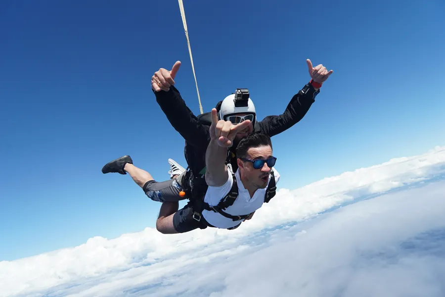 A tandem skydive in free fall above the clouds