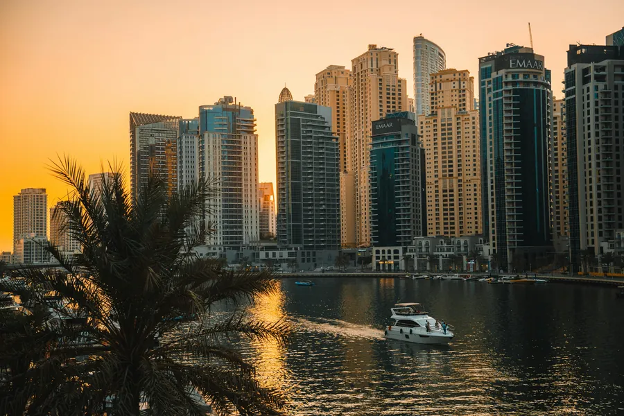 A yacht on Dubai Marina at sunset between the towers